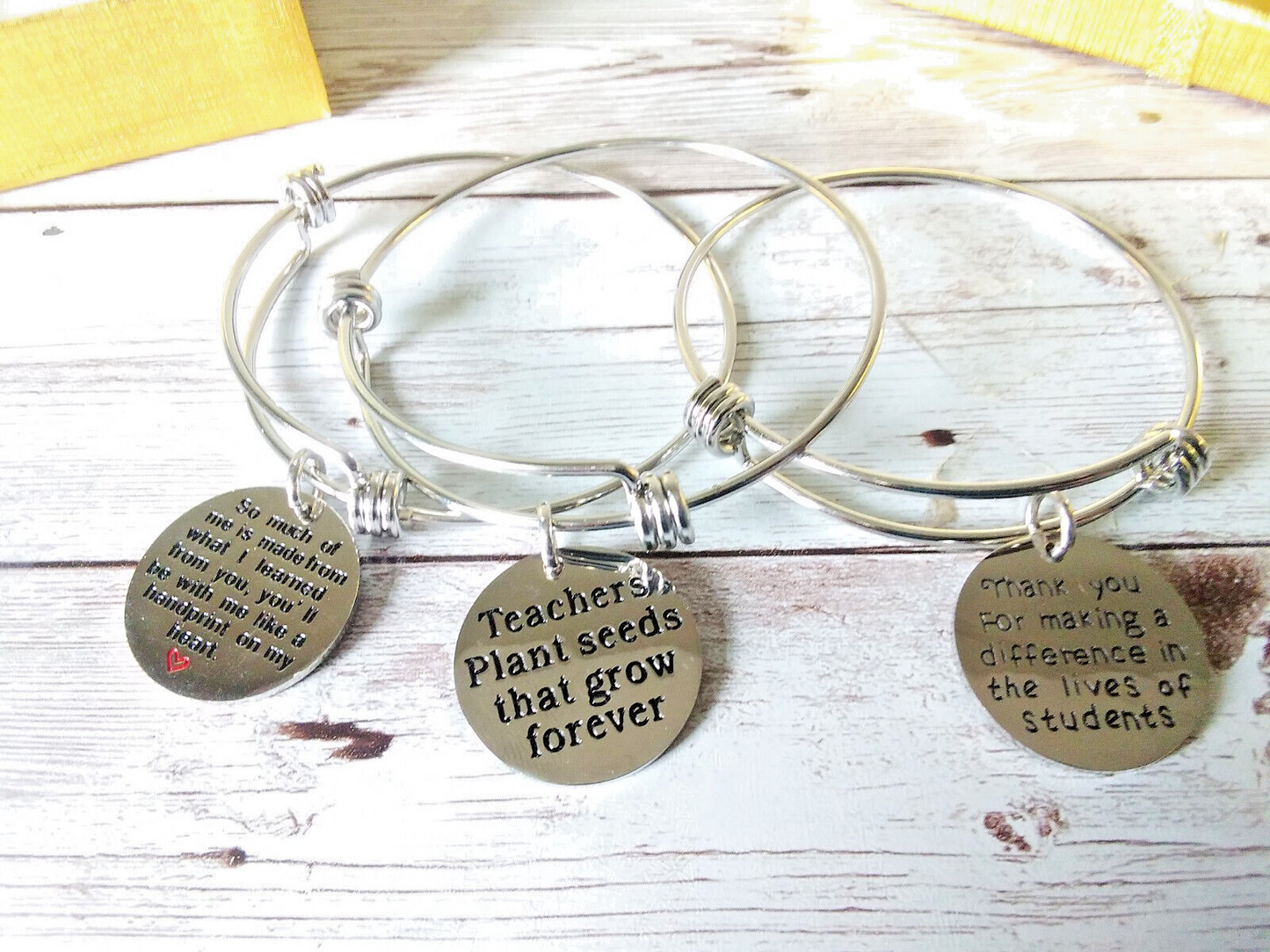 Close-up of teacher charm bracelets with "Thank you" engraving