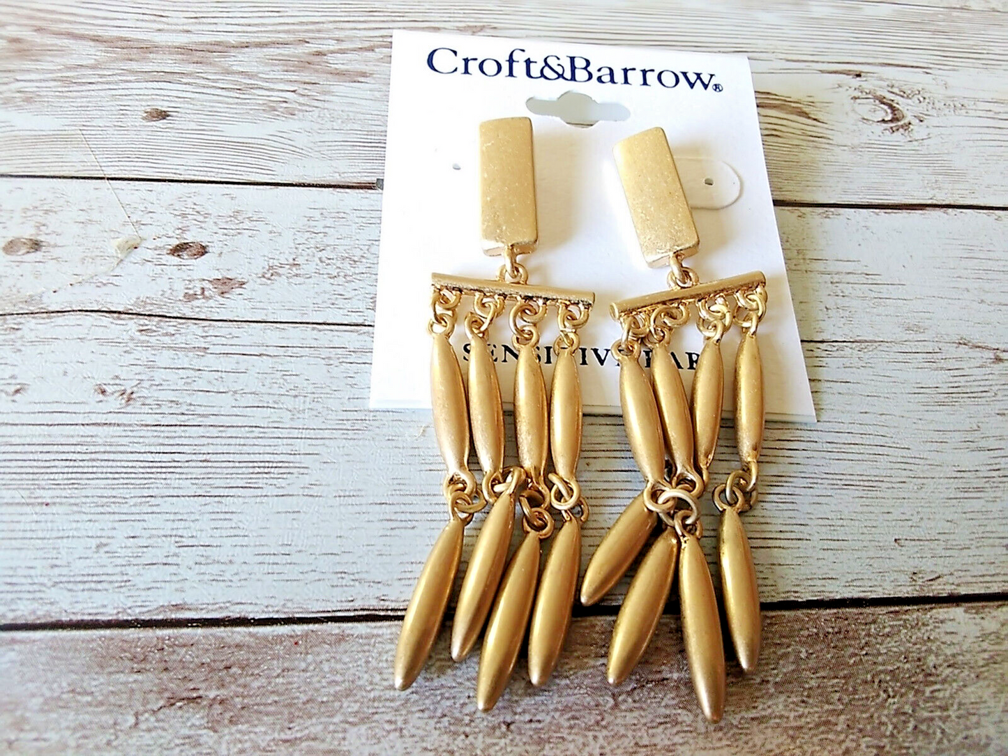Gold tone chandelier earrings by Croft & Barrow on a white wood background