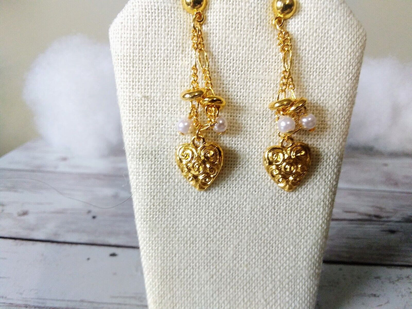 Detailed view of golden earrings with heartbeat and pearl elements