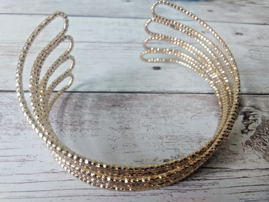 Gold tone cuff bracelet with winged design