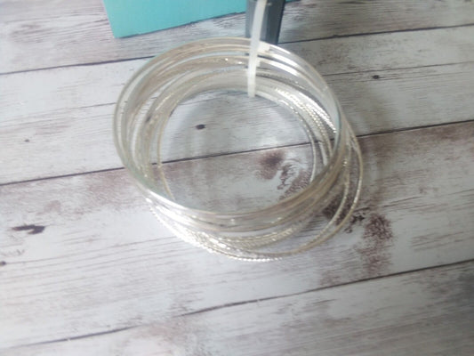 Metallic Melody: Set of 12 Chic Silver Bangle Bracelets by Massini