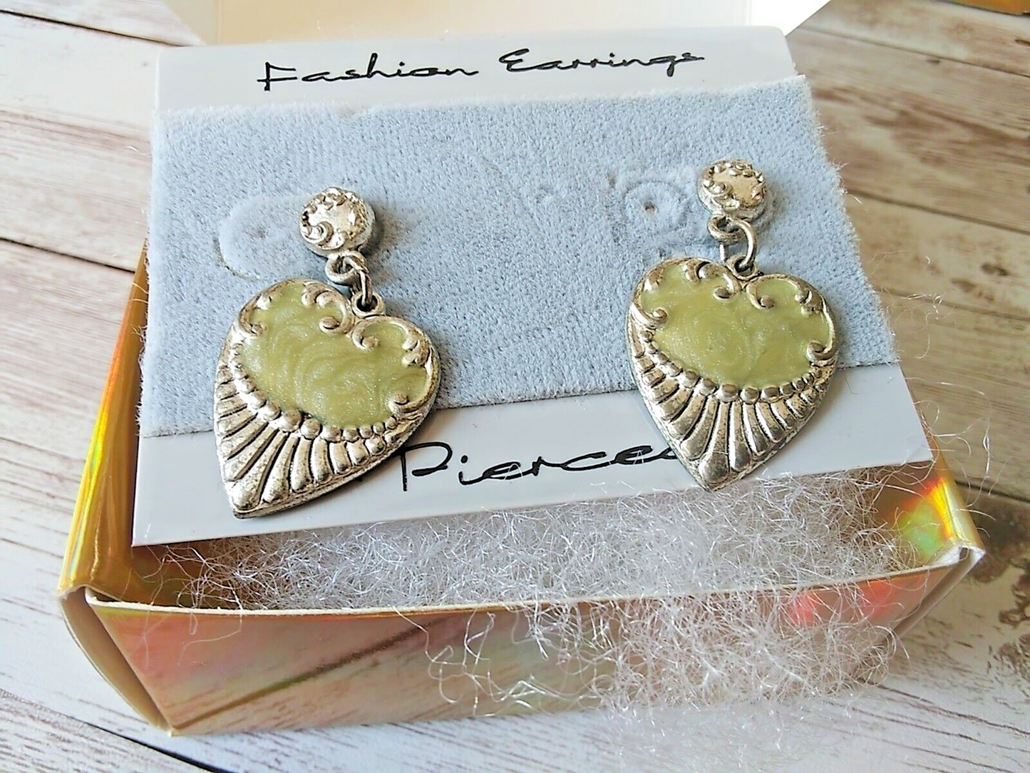 Classic 80s style earrings with charming green heart details in a gold gift box with cotton.