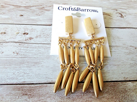 Gold tone chandelier earrings by Croft & Barrow on a white wood  background