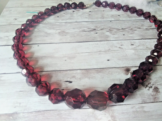 Shiny dark red beads increasing in size on necklace